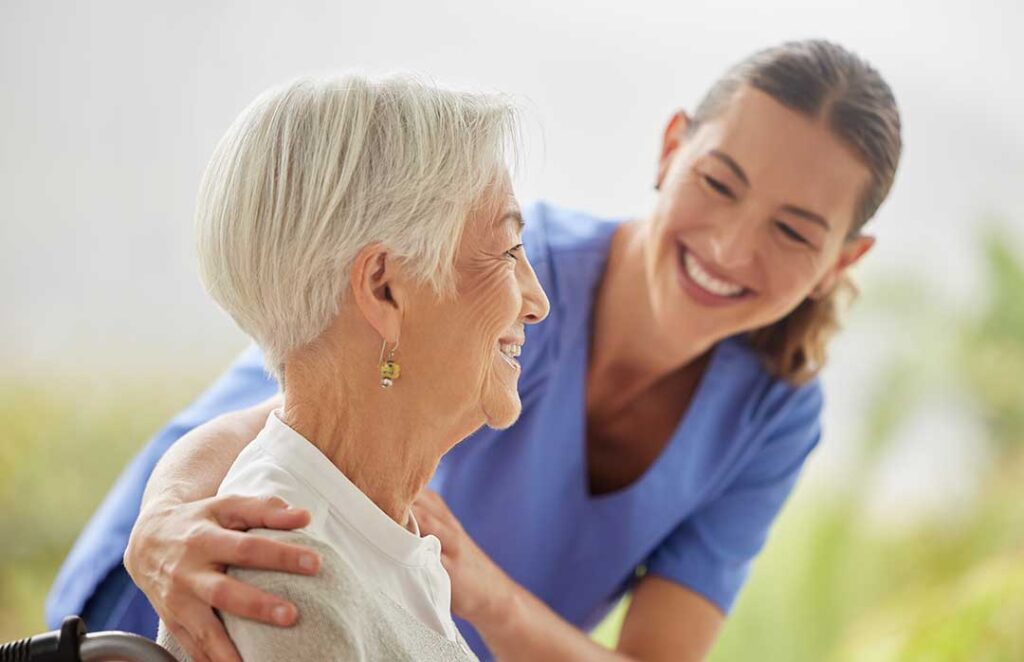 A diverse group of older adults sitting together in a bright, communal living room, engaged in friendly conversation.