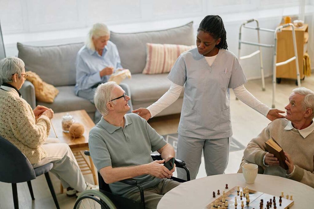 Caregiver reviews a medication chart with an older resident in a bright assisted living room.