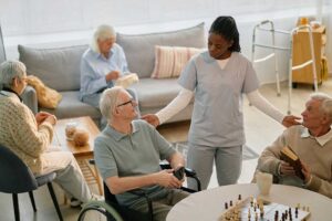 Caregiver reviews a medication chart with an older resident in a bright assisted living room.